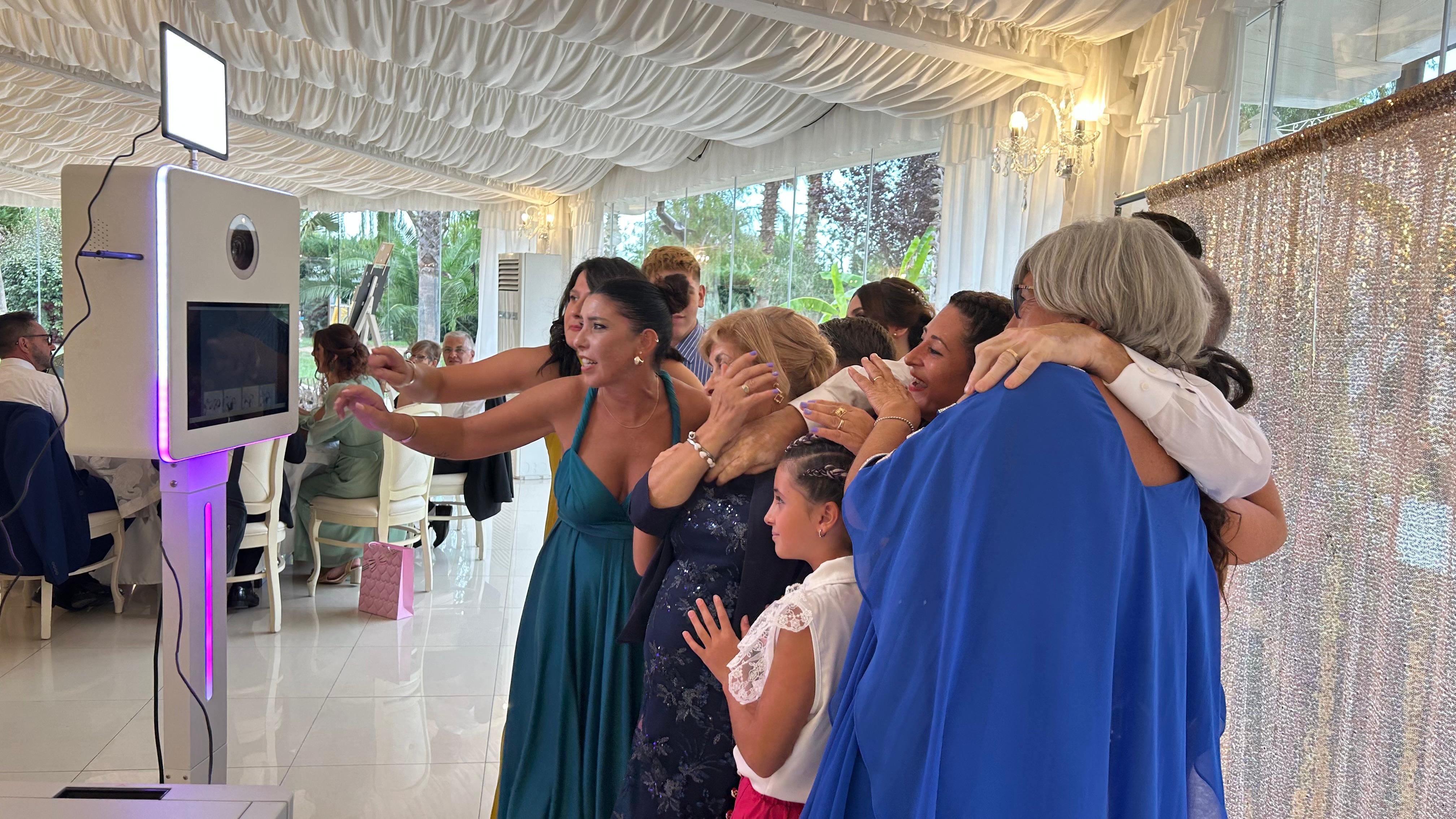 Invitati di un matrimonio si abbracciano davanti al photobooth